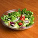 A Sabert clear plastic bowl filled with salad on a table.