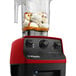 A Vitamix red Drink Machine with a 48 oz. container filled with bananas and ice cream.