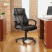 A black Alera office chair with wheels in front of a brick wall.