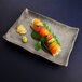 An Elite Global Solutions Santiago rectangular tray with sushi topped with salmon and mint.