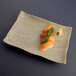 An Elite Global Solutions sandstone rectangular tray with sushi on it.