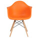 An orange plastic chair with wooden legs.