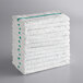 A stack of white bar towels with green stripes.