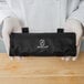 A person holding a black Mercer Culinary Garde Manger garnish kit case with a white text strap.