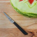 A Mercer Culinary Garde Manger Japanese style carving knife next to a watermelon with a design on it.