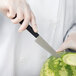 A hand in gloves holding a Mercer Culinary Japanese Style Carving Knife cuts a watermelon.