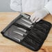 A person holding a Mercer Culinary Garde Manger 7-Piece Plating / Carving Knife Set in a black case.