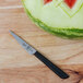 A Mercer Culinary Garde Manger knife next to a watermelon on a counter.