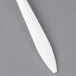 A close-up of a white plastic Dart F6BW fork on a gray surface.