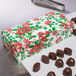 A Poinsettia holiday candy box on a counter next to chocolates.