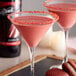 Two martini glasses filled with pink DaVinci Gourmet Classic Red Velvet Cake flavored drinks on a table.