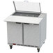 A Beverage-Air stainless steel sandwich prep table with clear lids open over food.