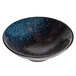 A white stoneware bowl with blue and black speckles.