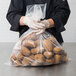 A person in gloves holding a LK Packaging plastic bag of potatoes.