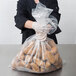 A person wearing gloves holding a LK Packaging heavy-duty plastic food bag full of potatoes.