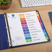 A binder with Avery customizable table of contents dividers with colorful labels on it.
