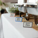 A blue ceramic table tent with a decal border on a table with name cards.