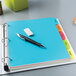 A binder with Avery Multi-Color Plastic Write/Erase Dividers on top.