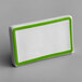 A white rectangular ceramic table tent sign with a green border.