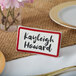 A maroon ceramic table tent with a decal border and the name Kayleigh Howard on it.
