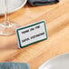 A teal ceramic table tent sign with a decal border on a table.