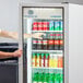 A person's arm opening the glass door of a white Beverage-Air refrigerated merchandiser.