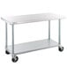 A white rectangular Regency stainless steel work table with black wheels.