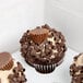 A white auto-popup window cupcake box with a chocolate peanut butter cupcake inside.