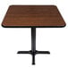 A square table with a black base and a reversible brown top.