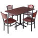 A Lancaster Table & Seating dining set with a cherry table top and black base and mahogany chairs with wood seats.