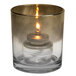 A Sterno Orla glass votive with a lit flame inside.