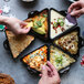 A group of people holding chips and dipping them into a Lodge mini cast iron triangular server filled with dips.