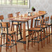 A Lancaster Table & Seating wooden table top with chairs and wine glasses.