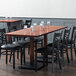 A Lancaster Table & Seating solid wood live edge table with mahogany finish and chairs at a restaurant.