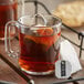A glass mug of Numi Organic Emperor's Pu-Erh tea with a tea bag in it.