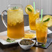 A glass of Numi Organic Citrus Green Iced Tea with ice and a lemon slice and a mint leaf on top.