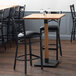 A Lancaster Table & Seating bar height table with chairs in a restaurant dining area.