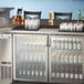 An Avantco back bar refrigerator with bottles and glasses inside.