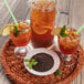 A pitcher of Numi iced tea with lemons and mint leaves on a wicker tray.