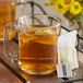 A glass mug of Numi Organic Amber Sun Turmeric Tea with a tea bag in it on a table.