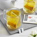 A glass mug of yellow Numi Organic Golden Tonic Turmeric Tea with a tea bag in it.