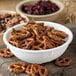 A Carlisle white melamine nappie bowl filled with pretzels and nuts on a table.