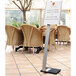 A Durable metal stand with an adjustable sign insert on a table in an outdoor catering setup.