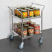 A Regency stainless steel utility cart full of canned food.