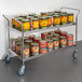 A Regency stainless steel utility cart full of cans.