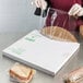 A person in gloves opening a box of LK Packaging clear plastic bags with a sandwich inside.