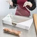 A woman wearing gloves using LK Packaging clear plastic wrap to cover a sandwich.