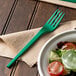 A green EcoChoice CPLA plastic fork on a plate of salad.