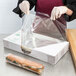 A person wearing gloves opening a box of LK Packaging BOPP clear plastic deli sandwich wrap.