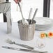 An American Metalcraft stainless steel utensil holder on a table with silverware.